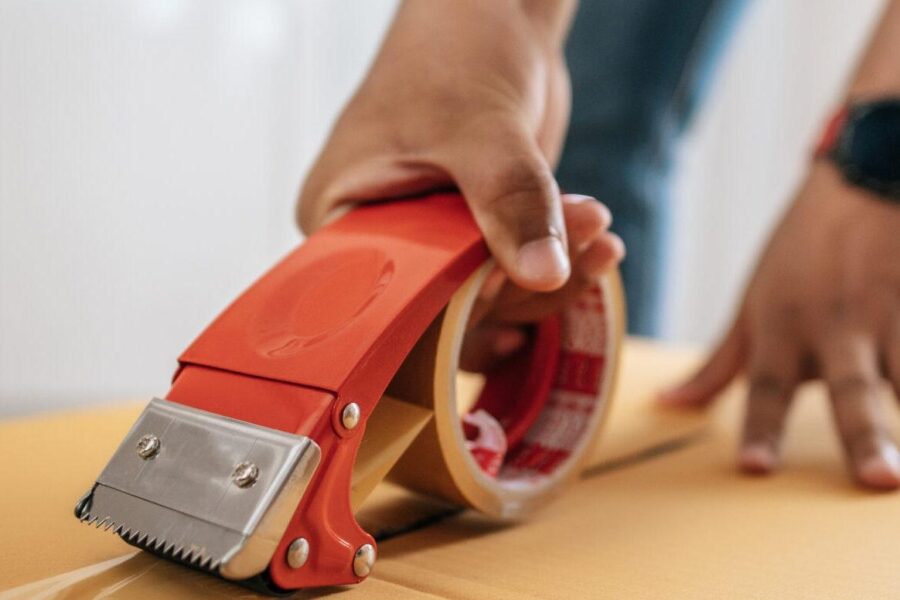 Male hand sealing big box with glue tape for packing Close up hand of man use glue tape to close cardboard box, sealing big box for packing moving, new house concept, Selective focus cardboard box,